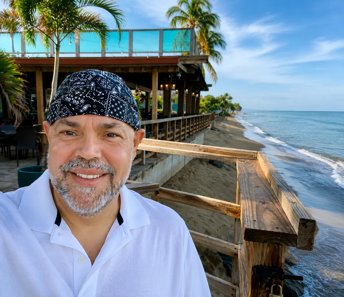 Wilfredo Piñeiro on a seaside boardwalk, the shoreline stretching away behind him