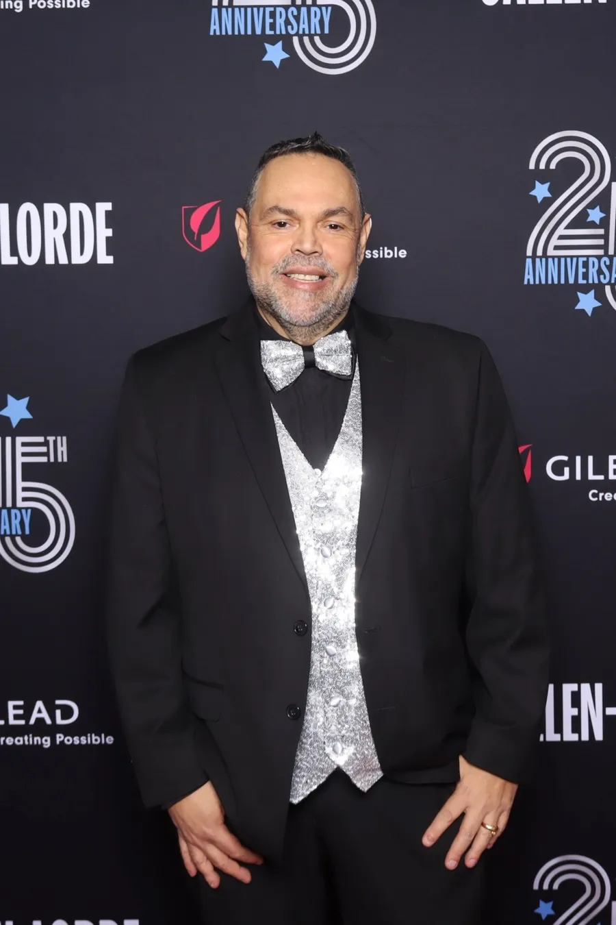 Wilfredo in a tuxedo with a sequinned waistcoat at a 25th-anniversary gala