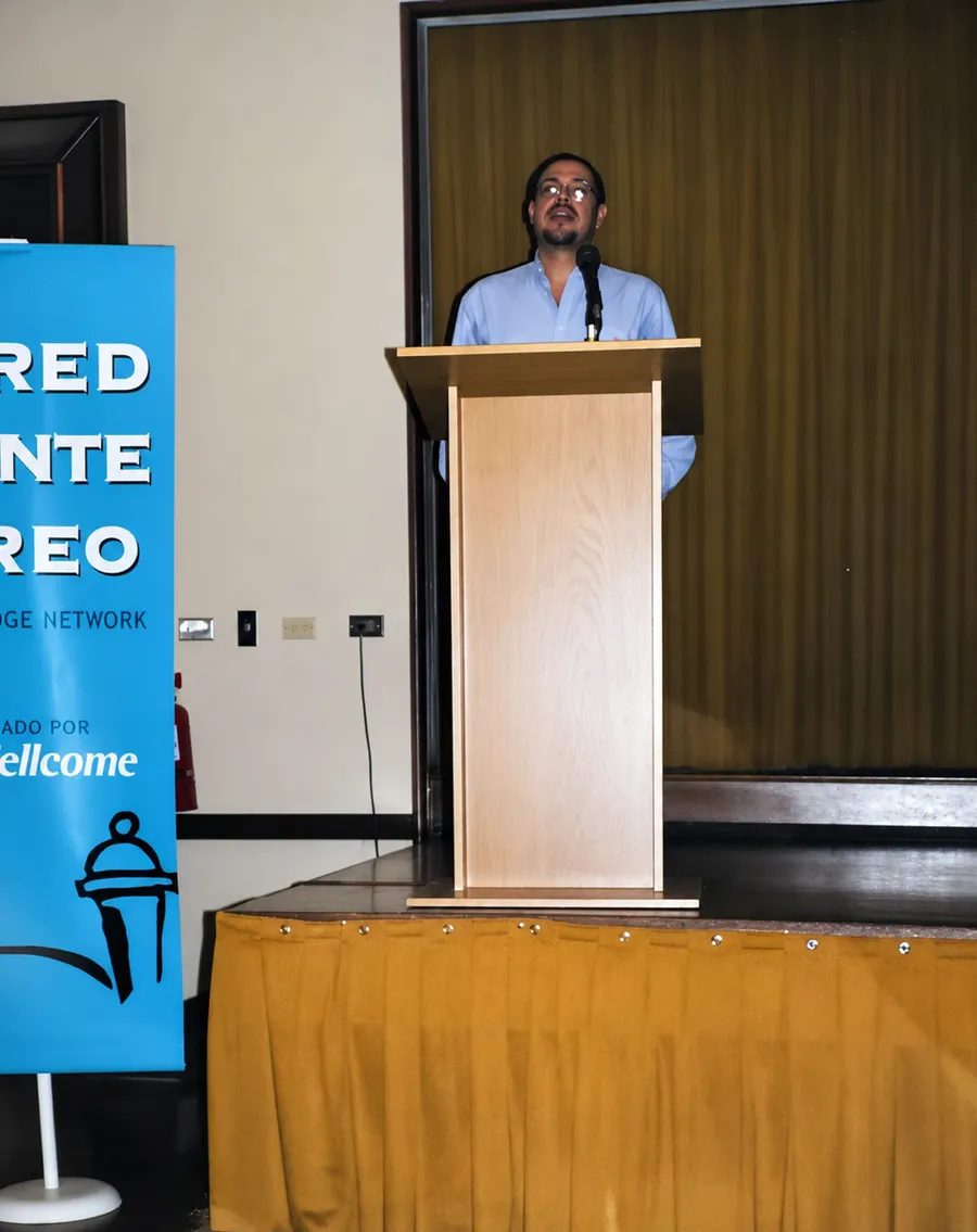 Wilfredo at a podium beside a Red Puente network banner