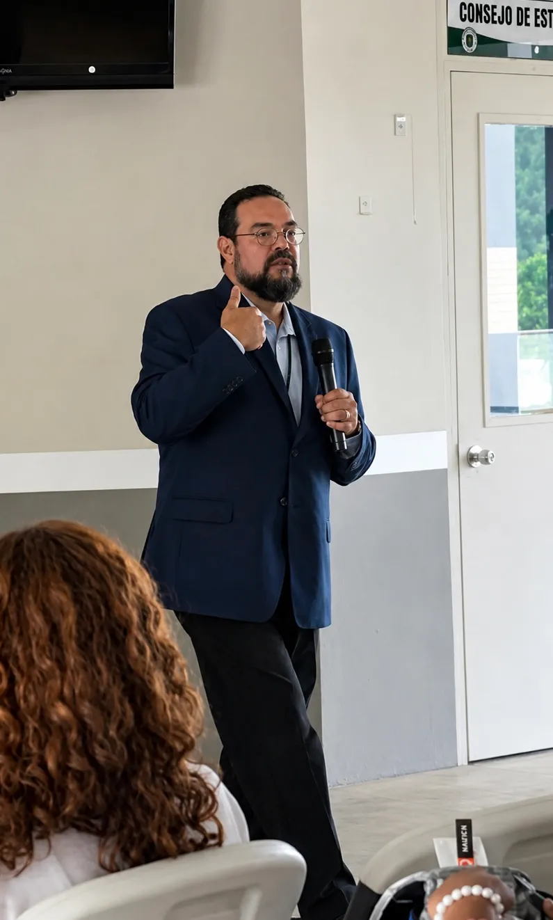 Wilfredo speaking with a microphone to a seated audience